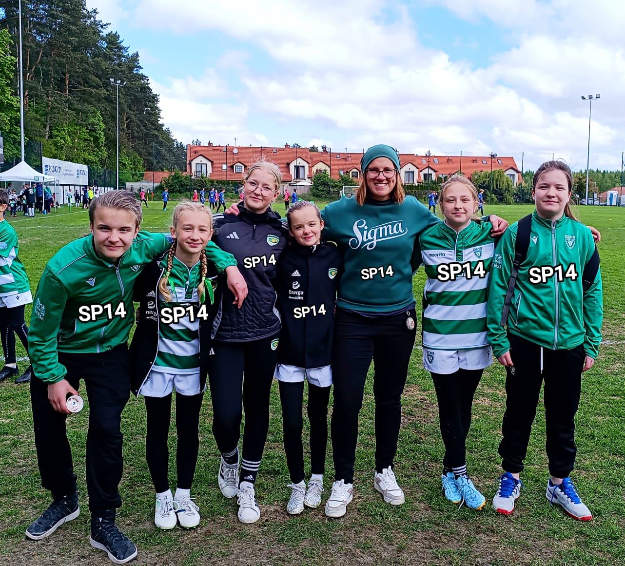 Grupa młodych zawodników z trenerką na boisku rugby.